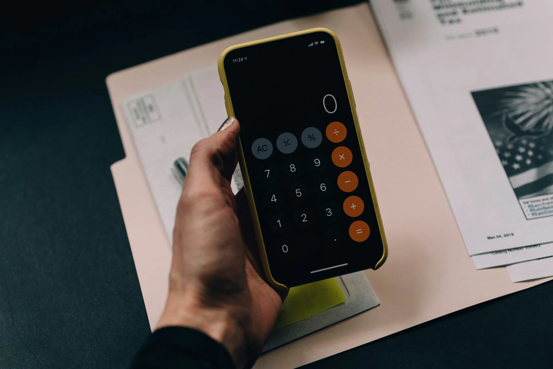 Calculator and documents Hand using a calculator beside printed documents on a desk