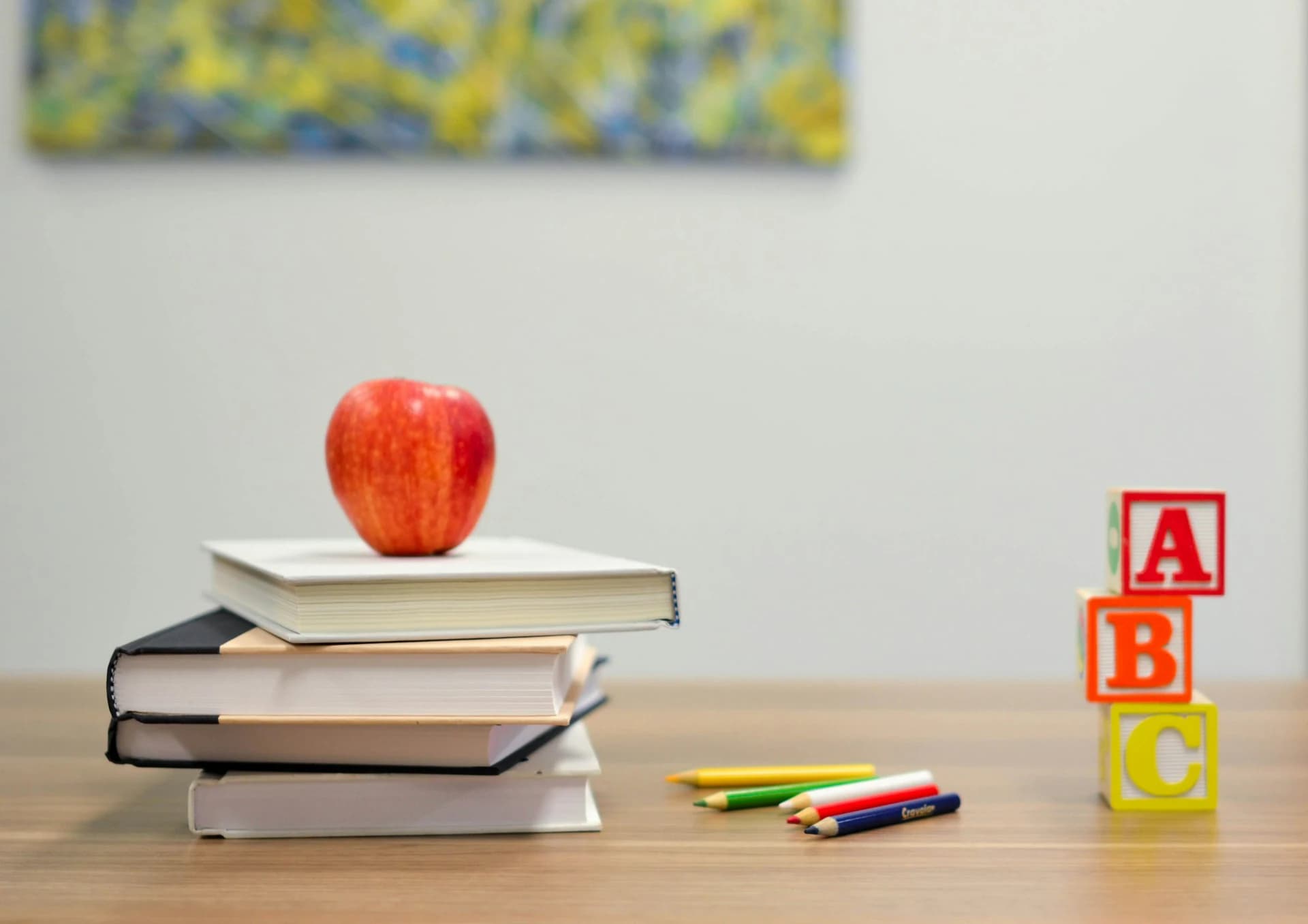 Classroom books and blocks Stack of school books with an apple and alphabet blocks on a classroom desk