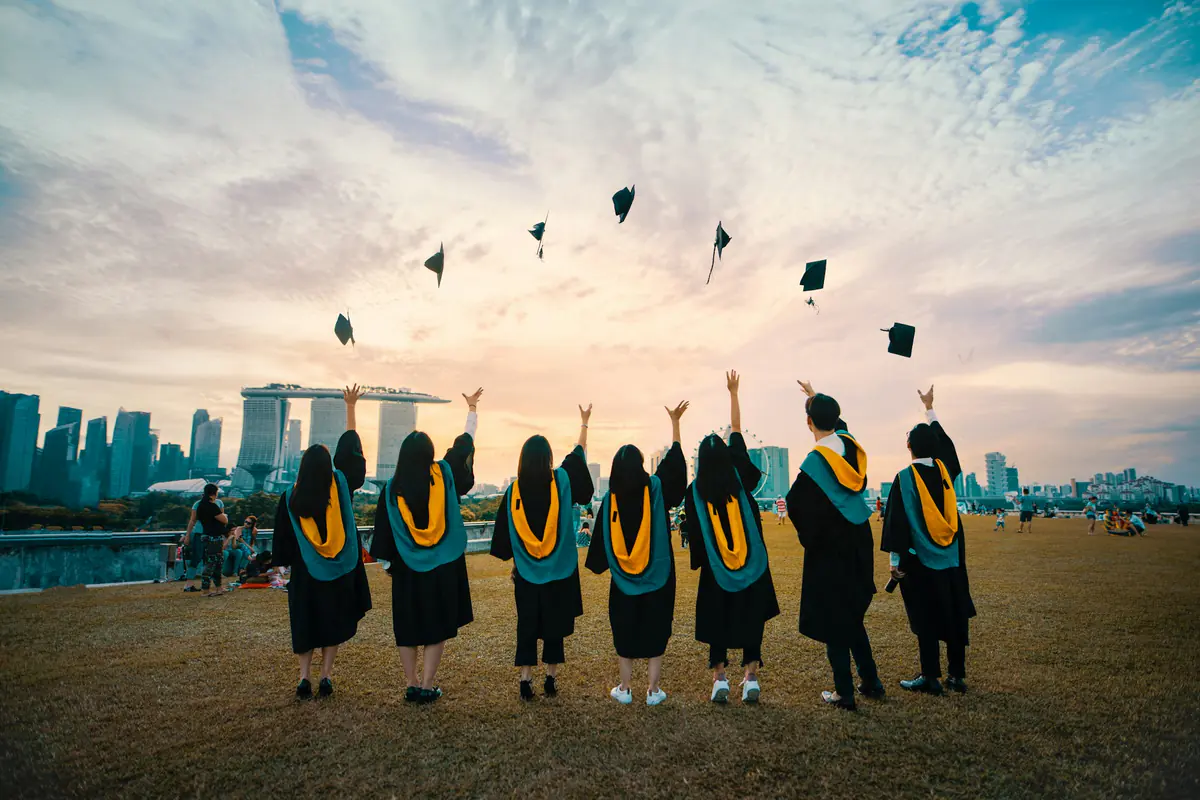 Graduation celebration University graduates in gowns throwing their caps into the air