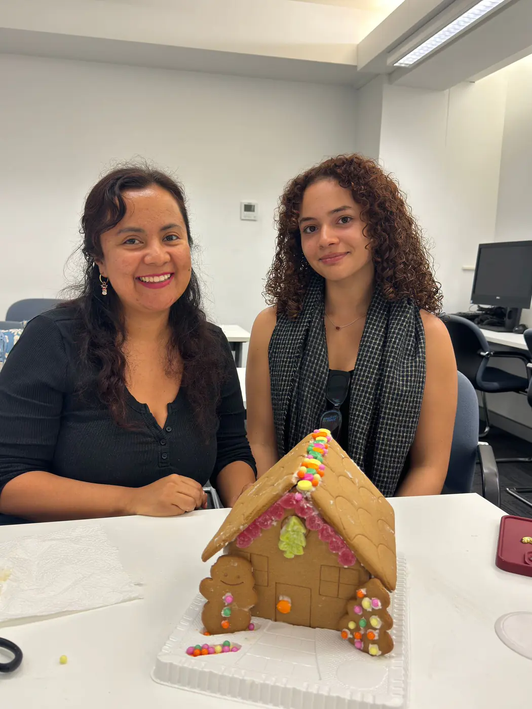 Decorated gingerbread house, 2025 Two students with the gingerbread house they decorated for Christmas