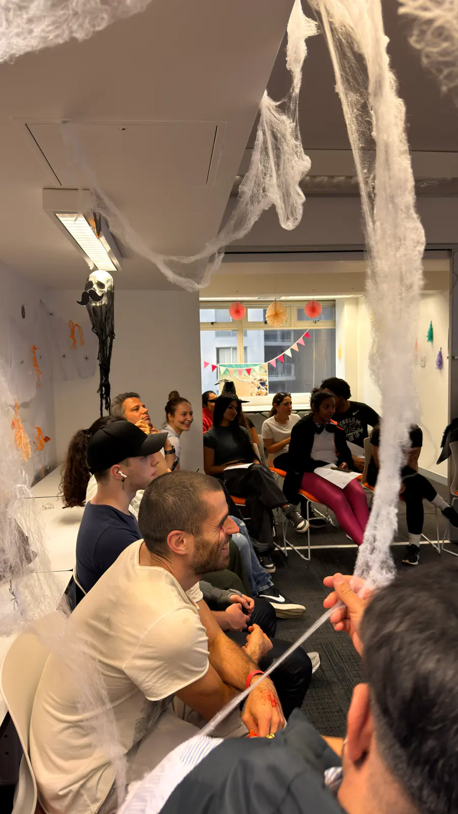 Cobweb decorations, Halloween 2025 Students seated in a classroom draped with Halloween cobweb decorations