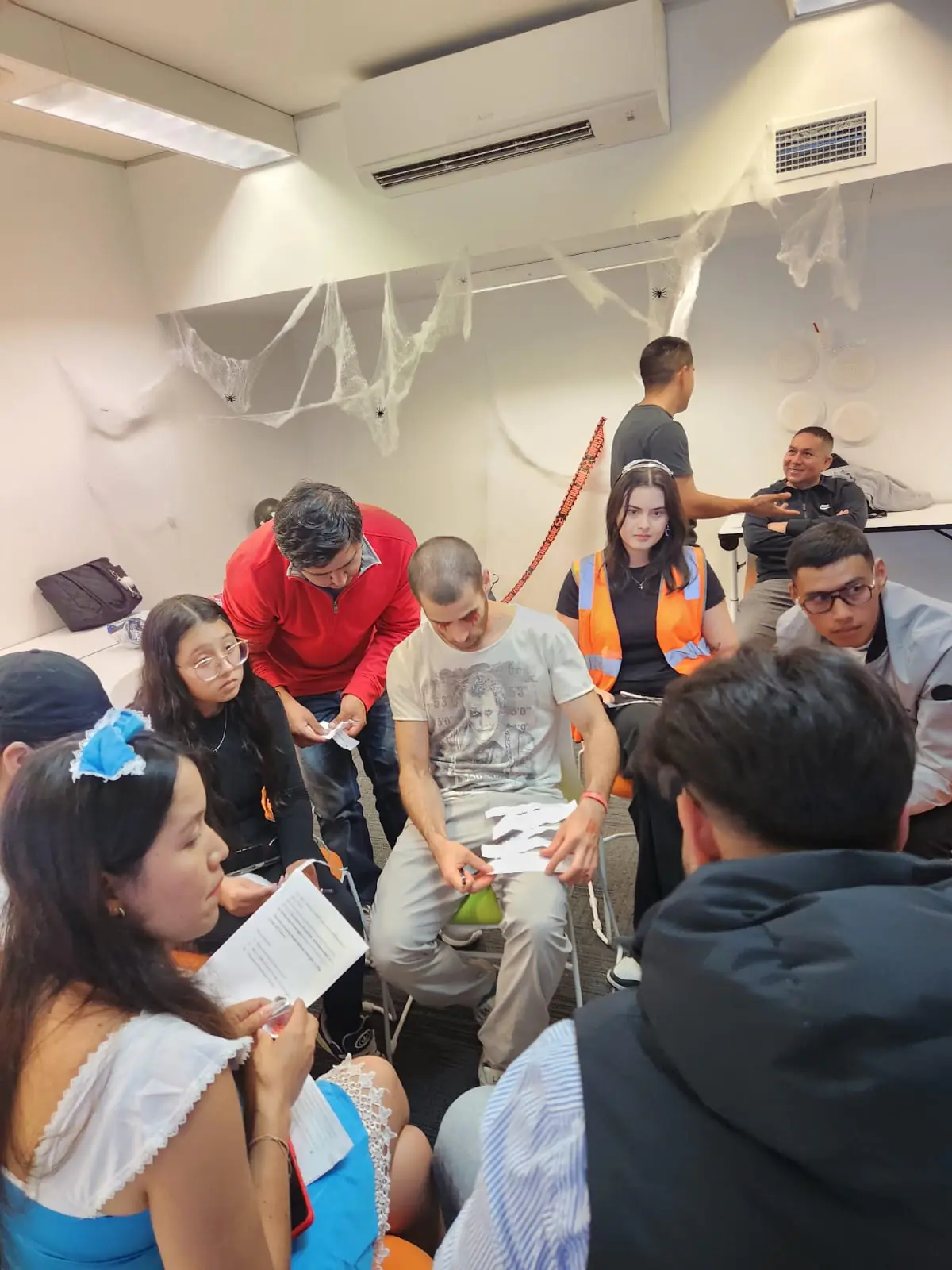 Halloween party games, 2025 Boston Institute students gathered around a table playing Halloween party games