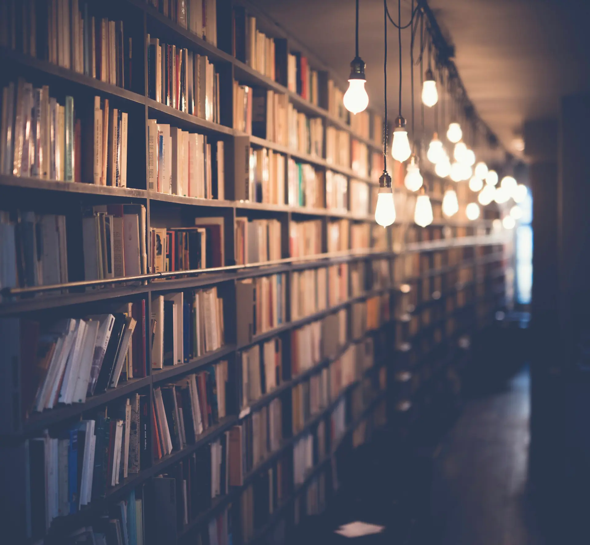 Long library aisle lined with bookshelves and hanging lights
