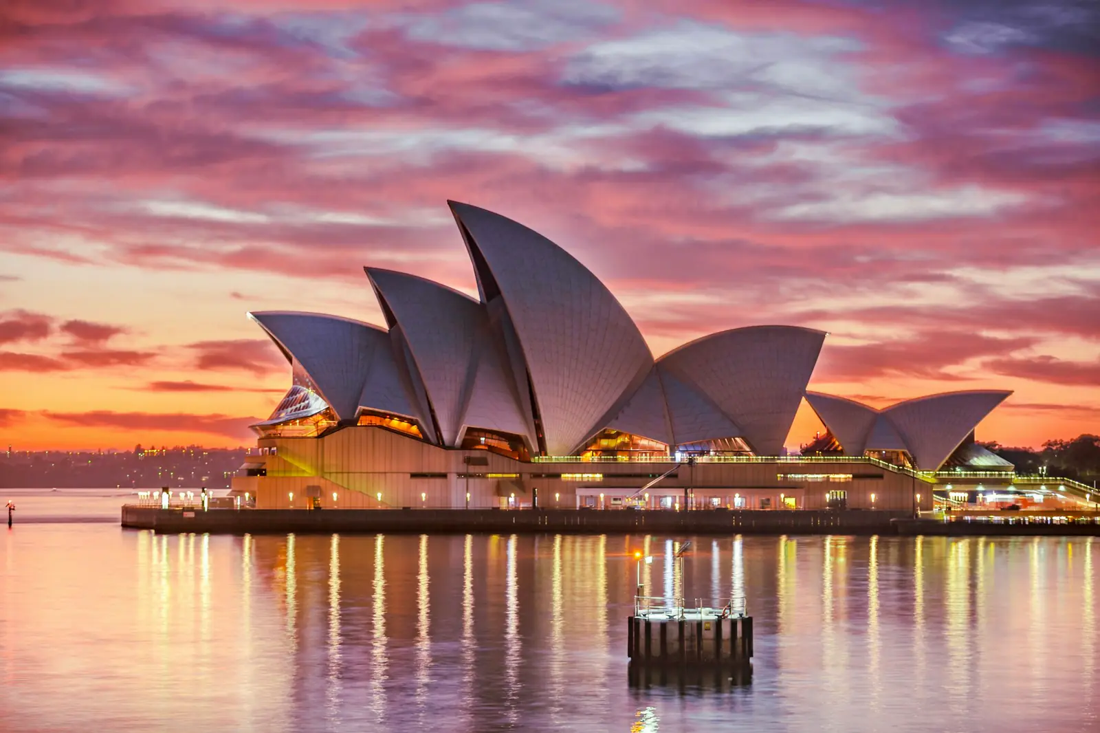 The Sydney Opera House lit by a pink and orange sunset over the harbour